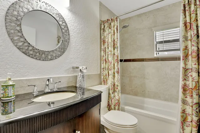 a bathroom with a granite countertop sink mirror toilet and bathtub