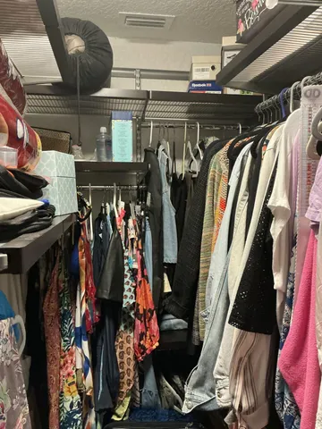 a view of walk in closet with clothes and shoes
