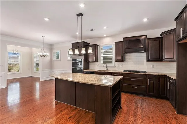 a kitchen with stainless steel appliances granite countertop wooden floor sink stove and wooden floor