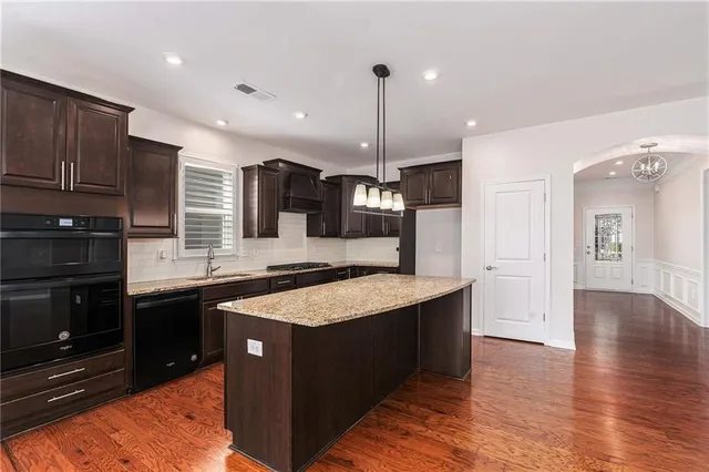 a kitchen with stainless steel appliances granite countertop a sink a stove and a wooden floors