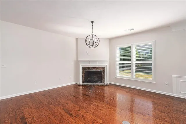 a view of an empty room with wooden floor fireplace and a window