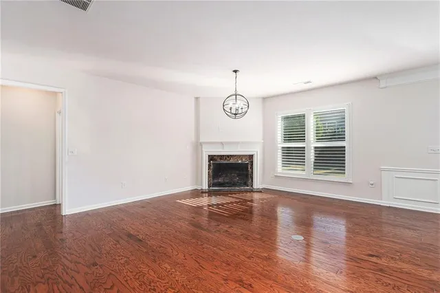 a view of an empty room with wooden floor fireplace and a window