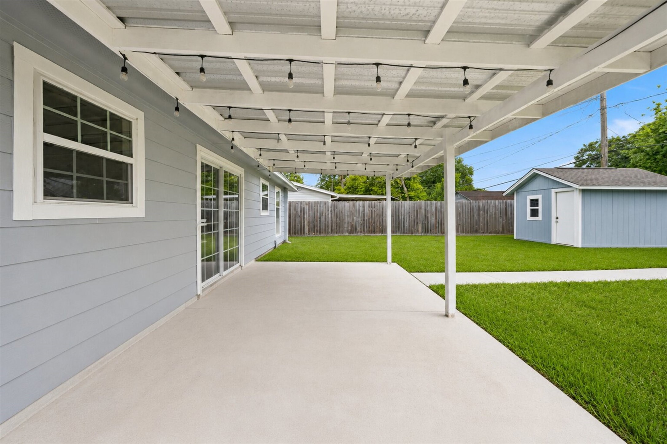 1306 Camden Road Pasadena, TX 77502 - Photo 14 of 16 Expansive covered patio with string lights, a large storage shed, and a beautifully maintained backyard, the perfect space to relax and entertain!