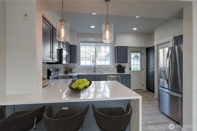 a kitchen with stainless steel appliances a sink a stove a refrigerator cabinets and dining table