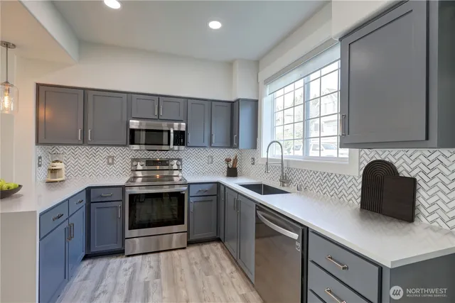 a kitchen with stainless steel appliances granite countertop a sink stove and microwave
