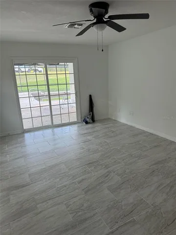 an empty room with wooden floor fan and a window