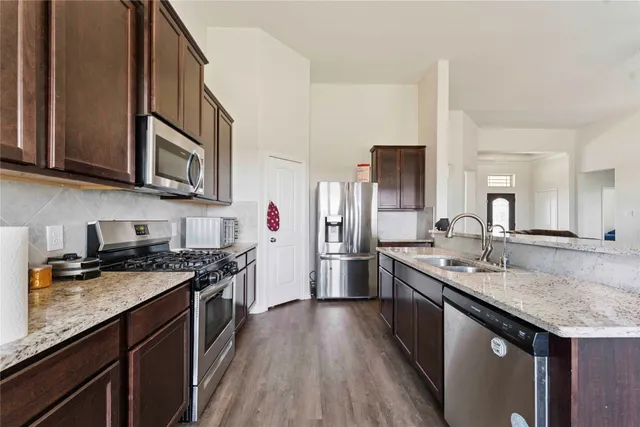 a kitchen with stainless steel appliances granite countertop a sink stove and refrigerator