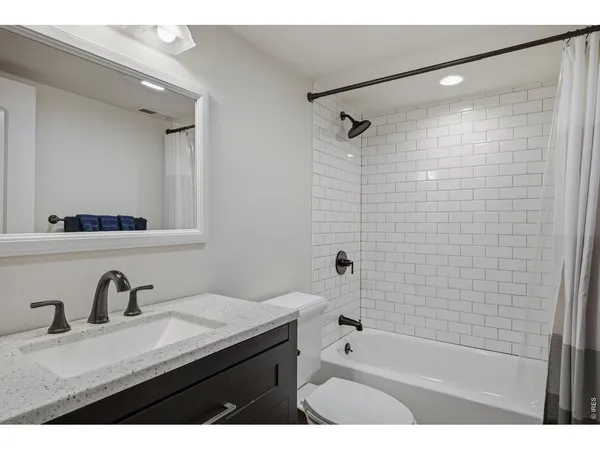 a bathroom with a granite countertop sink a mirror a bathtub and shower