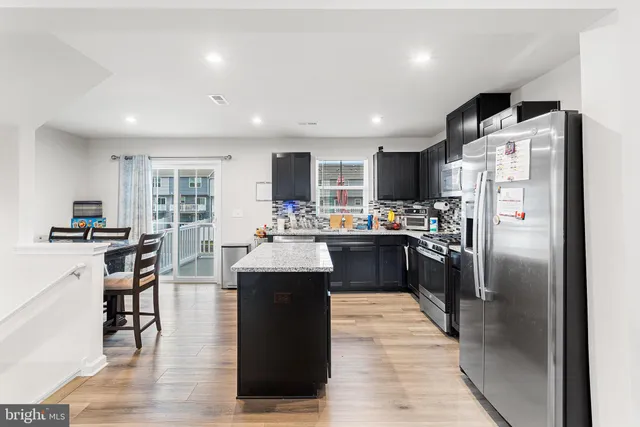 a kitchen with stainless steel appliances kitchen island granite countertop a refrigerator a sink dishwasher a stove and a refrigerator