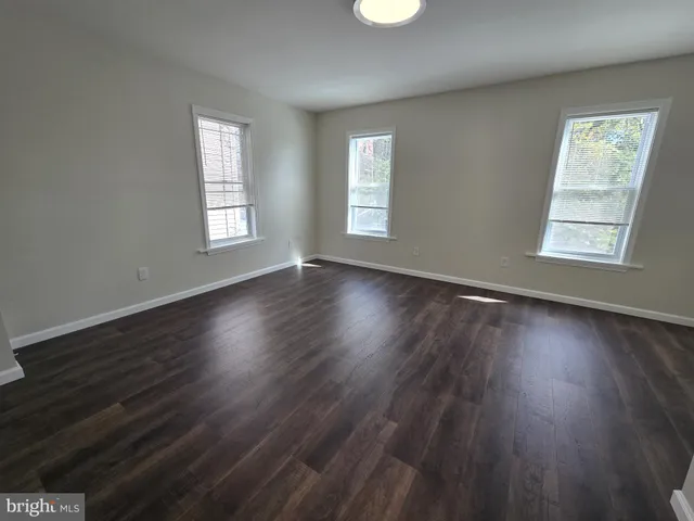 a view of an empty room with wooden floor and window