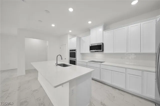 a kitchen with white cabinets appliances and sink