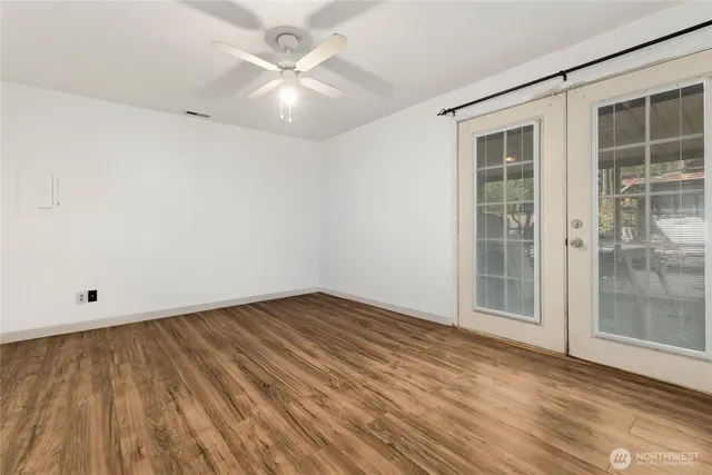 an empty room with wooden floor and windows