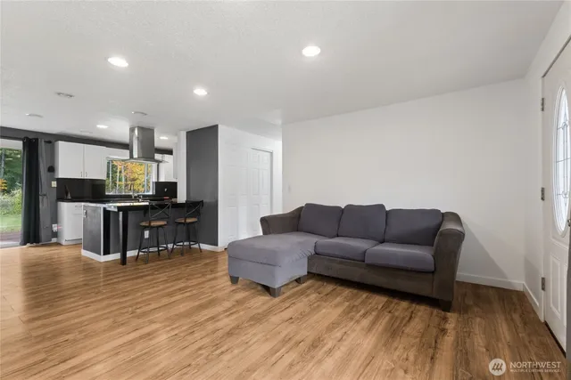 a living room with furniture and kitchen view with wooden floor