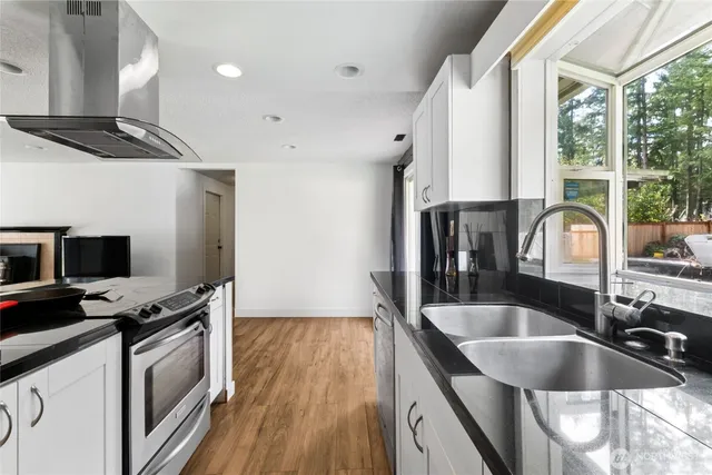 a kitchen with granite countertop a sink a counter space appliances and cabinets