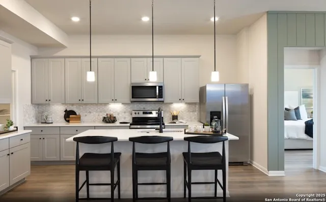 a kitchen with stainless steel appliances kitchen island granite countertop a dining table chairs sink and microwave