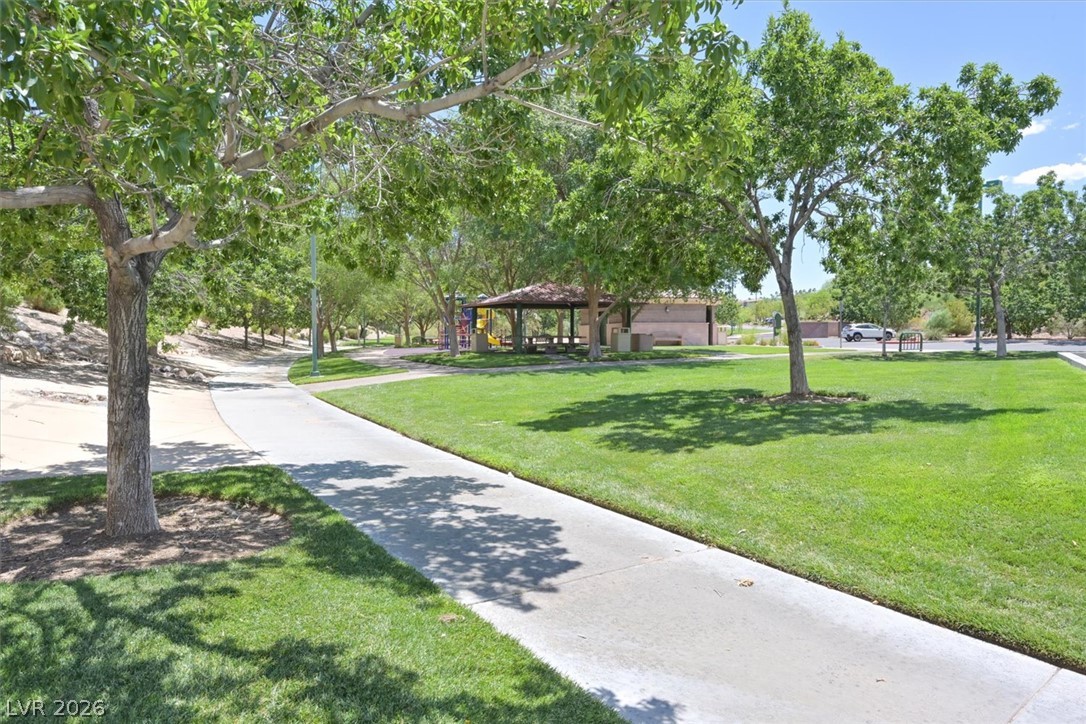 1259 Moon Vision Street Henderson, NV 89052 - Photo 51 of 53 A vibrant green park space with mature trees, a winding sidewalk, and a shaded picnic area.