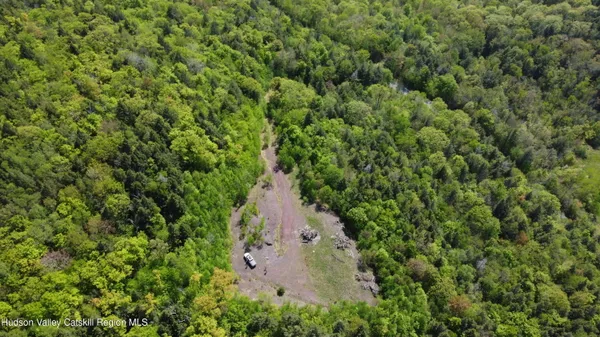 an aerial view of residential house with outdoor space and trees all around