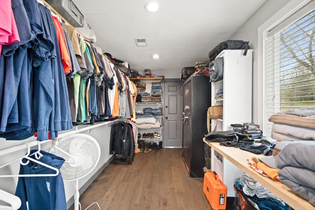 an empty room with wooden floor closet and windows