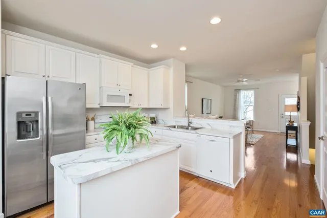 a kitchen with stainless steel appliances kitchen island granite countertop a refrigerator and a sink