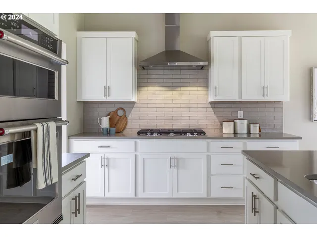 a kitchen with stainless steel appliances granite countertop a stove a sink and white cabinets