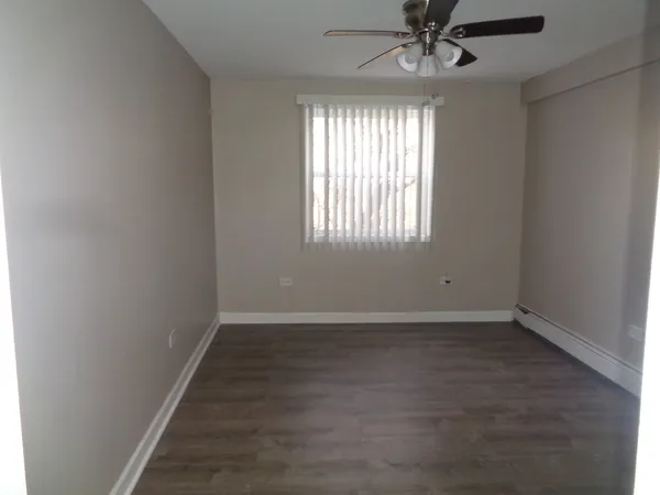 an empty room with wooden floor chandelier fan and windows