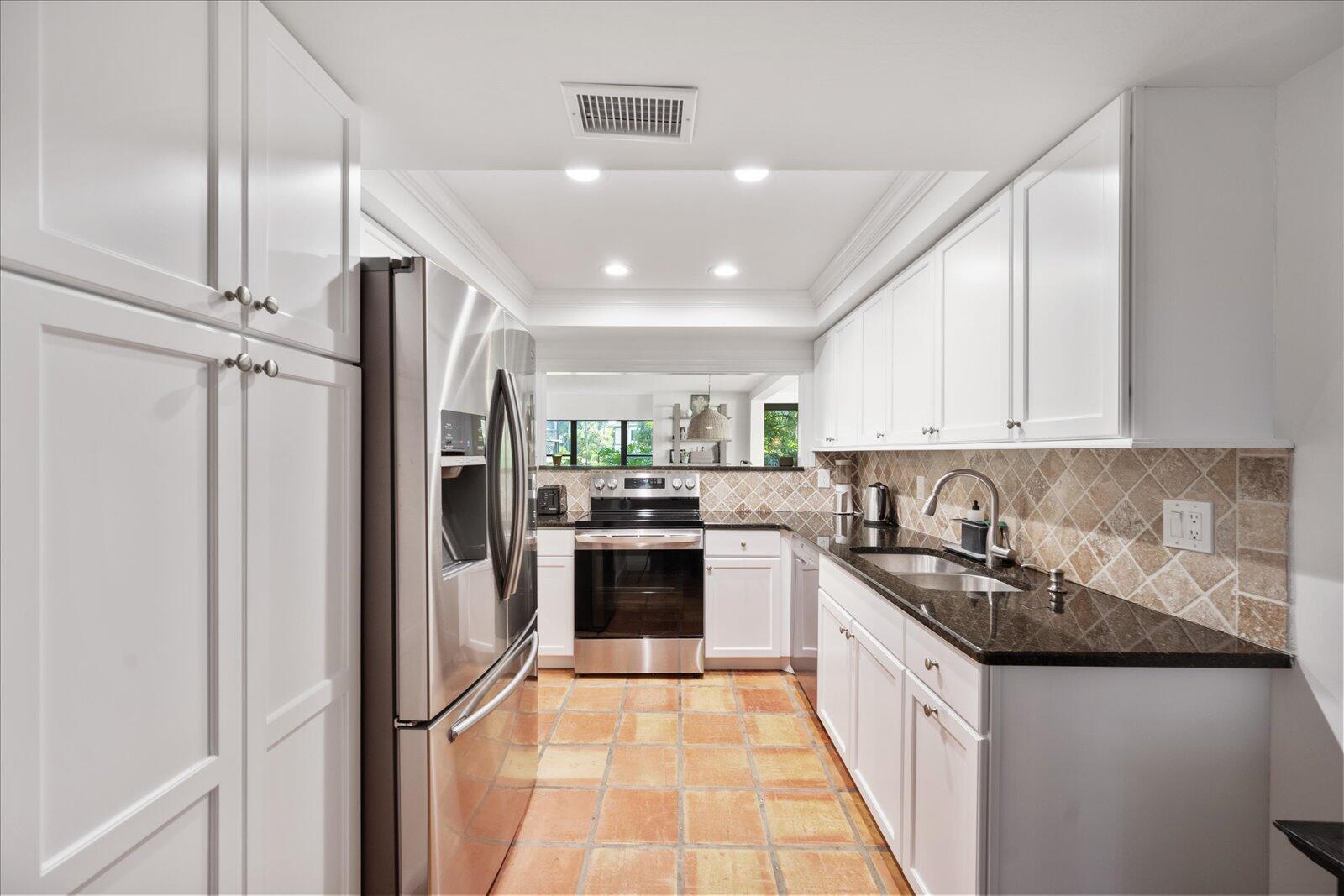 13307 Polo Club Road, Unit C106 Wellington, FL 33414 - Photo 14 of 25 a kitchen with stainless steel appliances granite countertop a refrigerator a sink dishwasher a stove and white cabinets with wooden floor