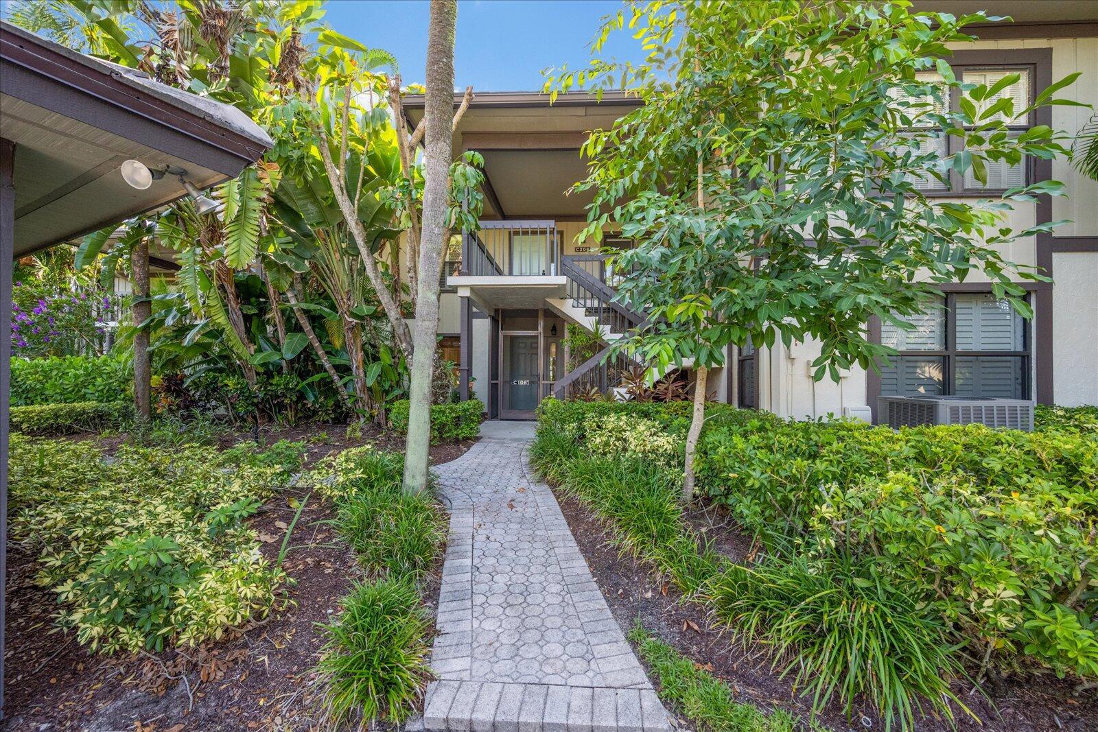 13307 Polo Club Road, Unit C106 Wellington, FL 33414 - Photo 3 of 25 a front view of a house with plants and trees
