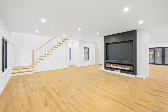 a view of an empty room with wooden floor and windows