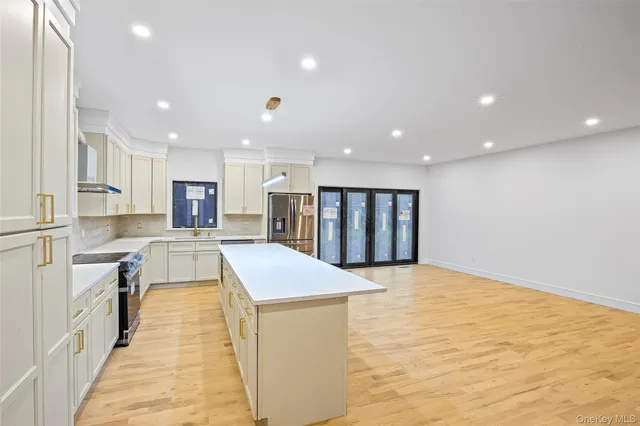 a large kitchen with kitchen island a stove a sink a refrigerator and white cabinets