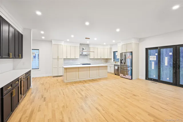 a large white kitchen with wooden floors stainless steel appliances and a window