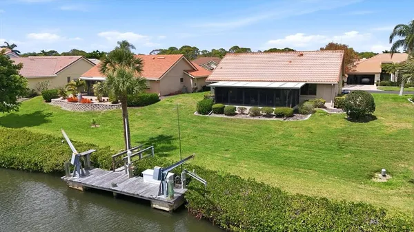 a view of a lake with lawn chairs and large trees