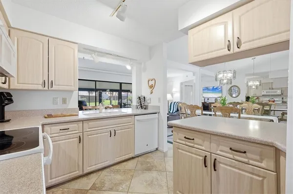 a kitchen with kitchen island granite countertop white cabinets white stainless steel appliances with a sink and dishwasher