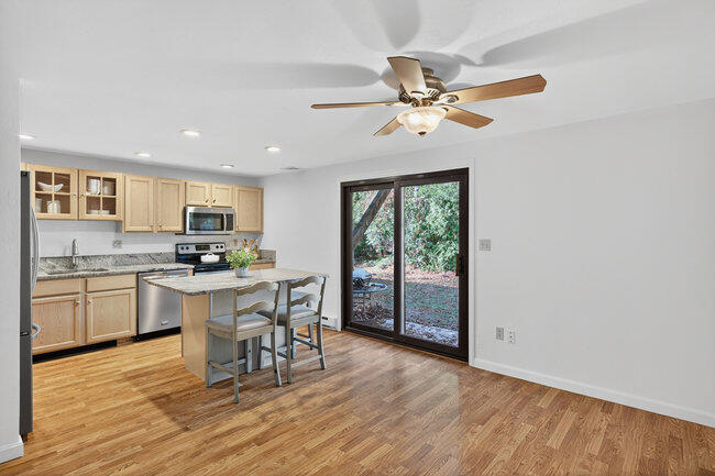 195 Falmouth Road, Unit 10E Mashpee, MA 02649 - Photo 11 of 33 a kitchen with stainless steel appliances granite countertop a stove top oven a refrigerator a sink dishwasher with a dining table and chairs with wooden floor
