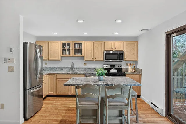 a kitchen with granite countertop cabinets stainless steel appliances a sink and a window