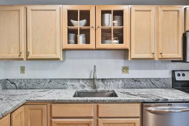 a kitchen with granite countertop stainless steel appliances granite countertop white cabinets and a window
