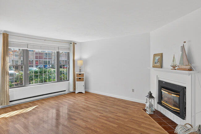 195 Falmouth Road, Unit 10E Mashpee, MA 02649 - Photo 4 of 33 a view of empty room with wooden floor and fireplace