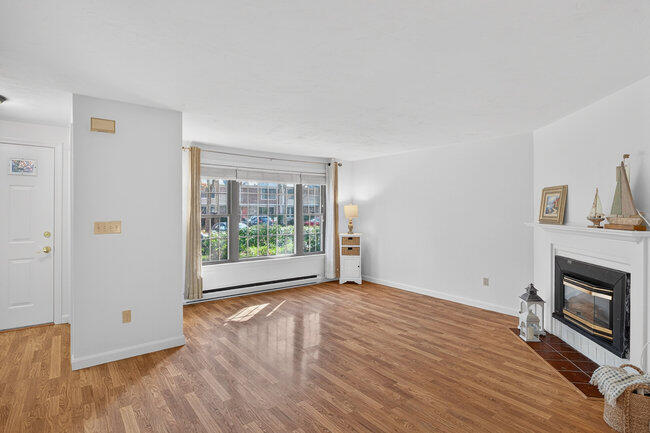195 Falmouth Road, Unit 10E Mashpee, MA 02649 - Photo 6 of 33 a view of empty room with wooden floor and fireplace
