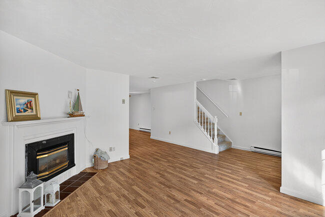 195 Falmouth Road, Unit 10E Mashpee, MA 02649 - Photo 8 of 33 a view of an empty room with wooden floor and a fireplace