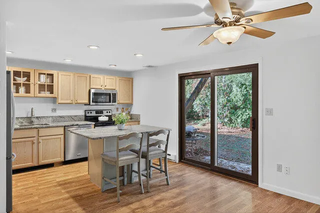 a kitchen with stainless steel appliances granite countertop a stove a refrigerator a microwave oven with a dining table and chairs with wooden floor