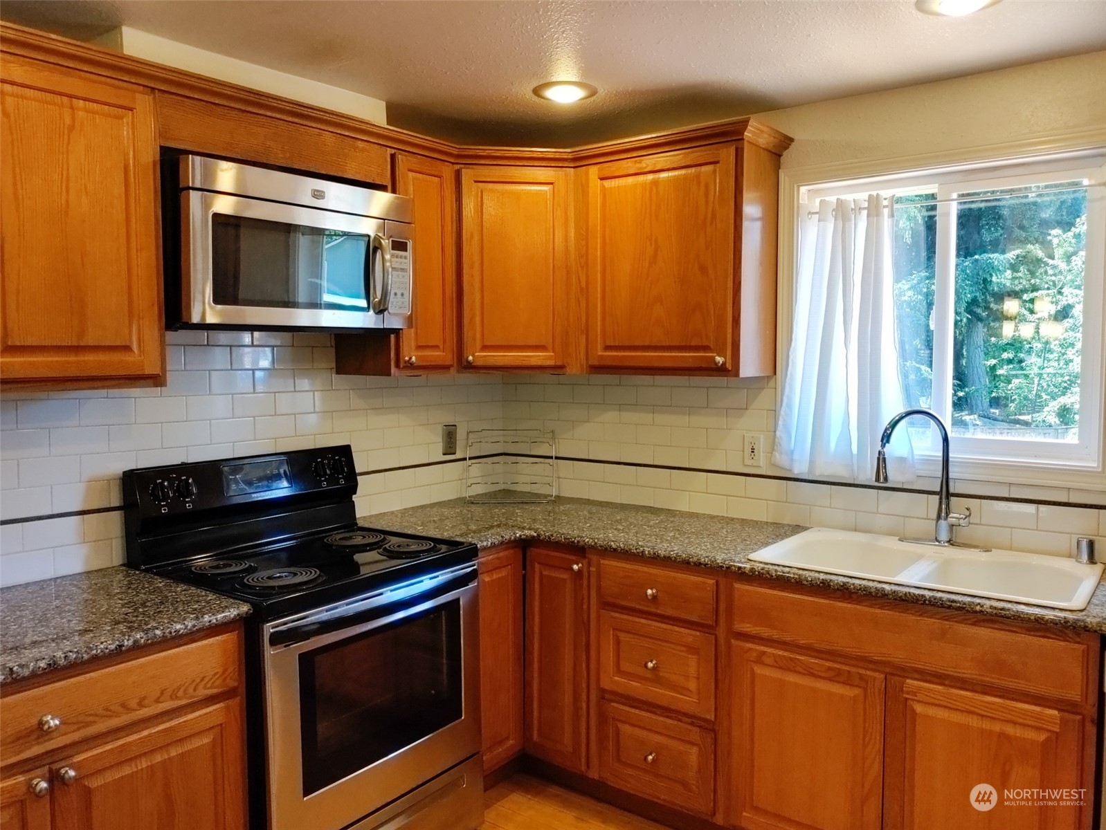 16032 Spanaway Loop Road South Spanaway, WA 98387 - Photo 7 of 28 a kitchen with granite countertop cabinets stainless steel appliances and a sink