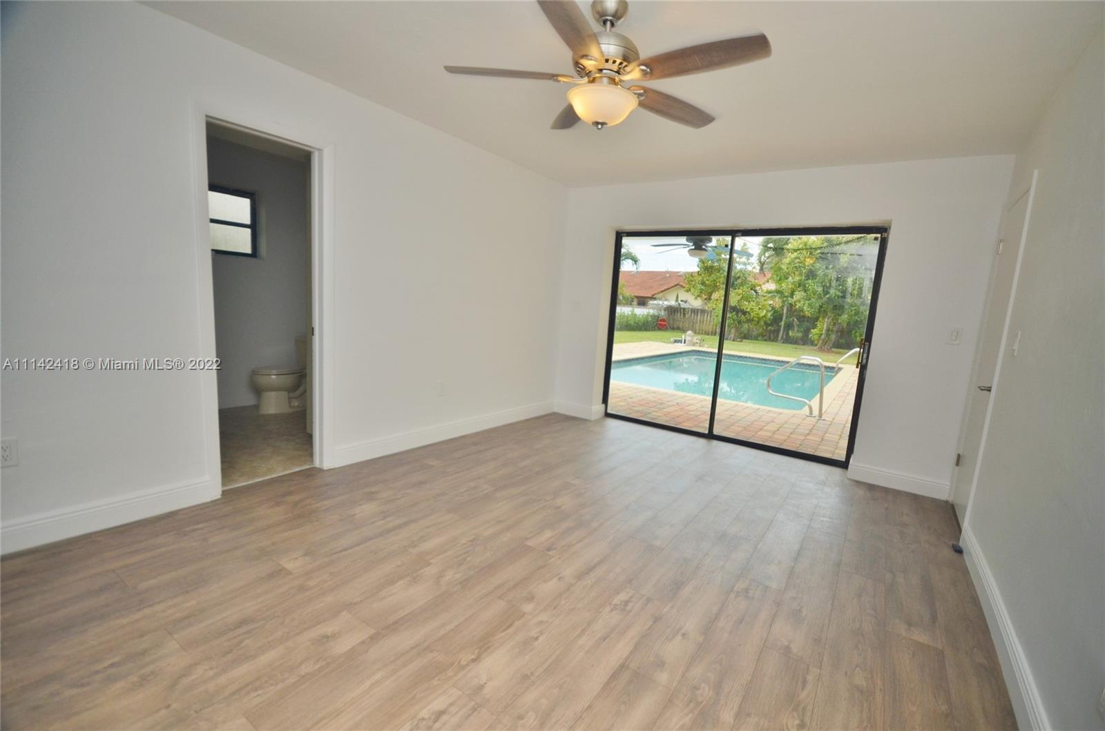 6760 Royal Melbourne Drive Hialeah, FL 33015 - Photo 22 of 36 an empty room with wooden floor fan and windows