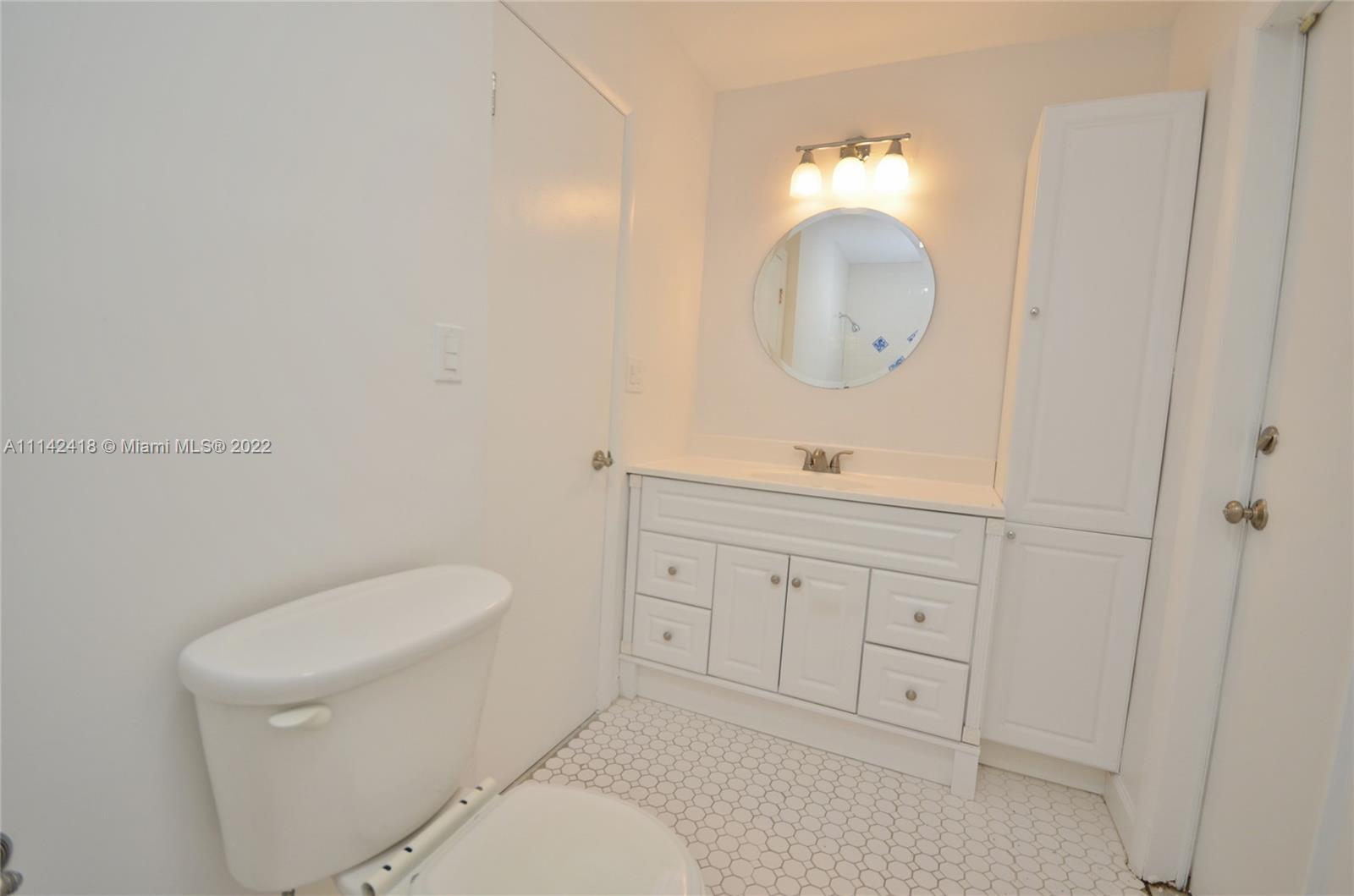 6760 Royal Melbourne Drive Hialeah, FL 33015 - Photo 23 of 36 a bathroom with a toilet a sink a mirror and vanity