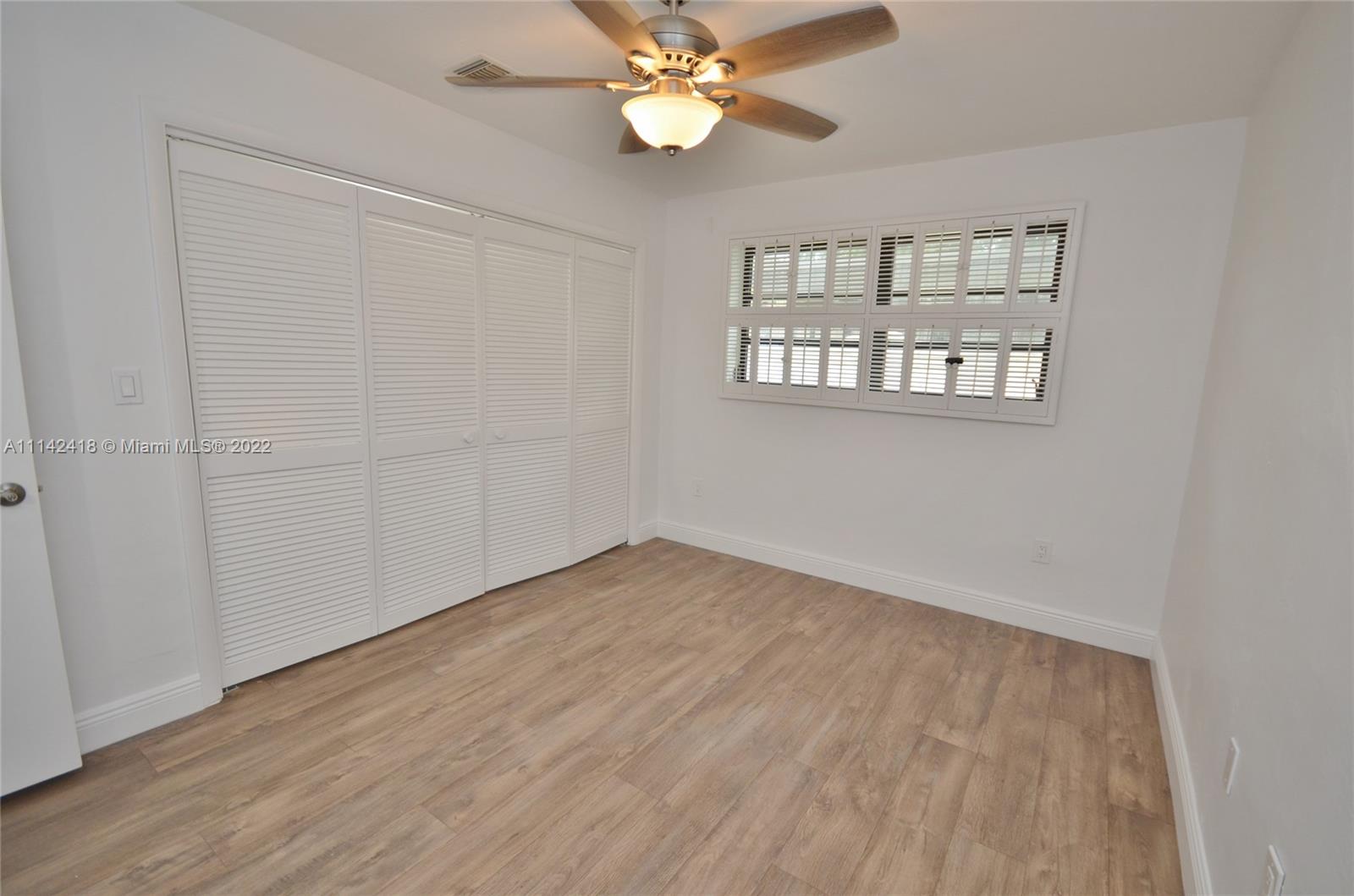 6760 Royal Melbourne Drive Hialeah, FL 33015 - Photo 25 of 36 an empty room with wooden floor chandelier fan and windows