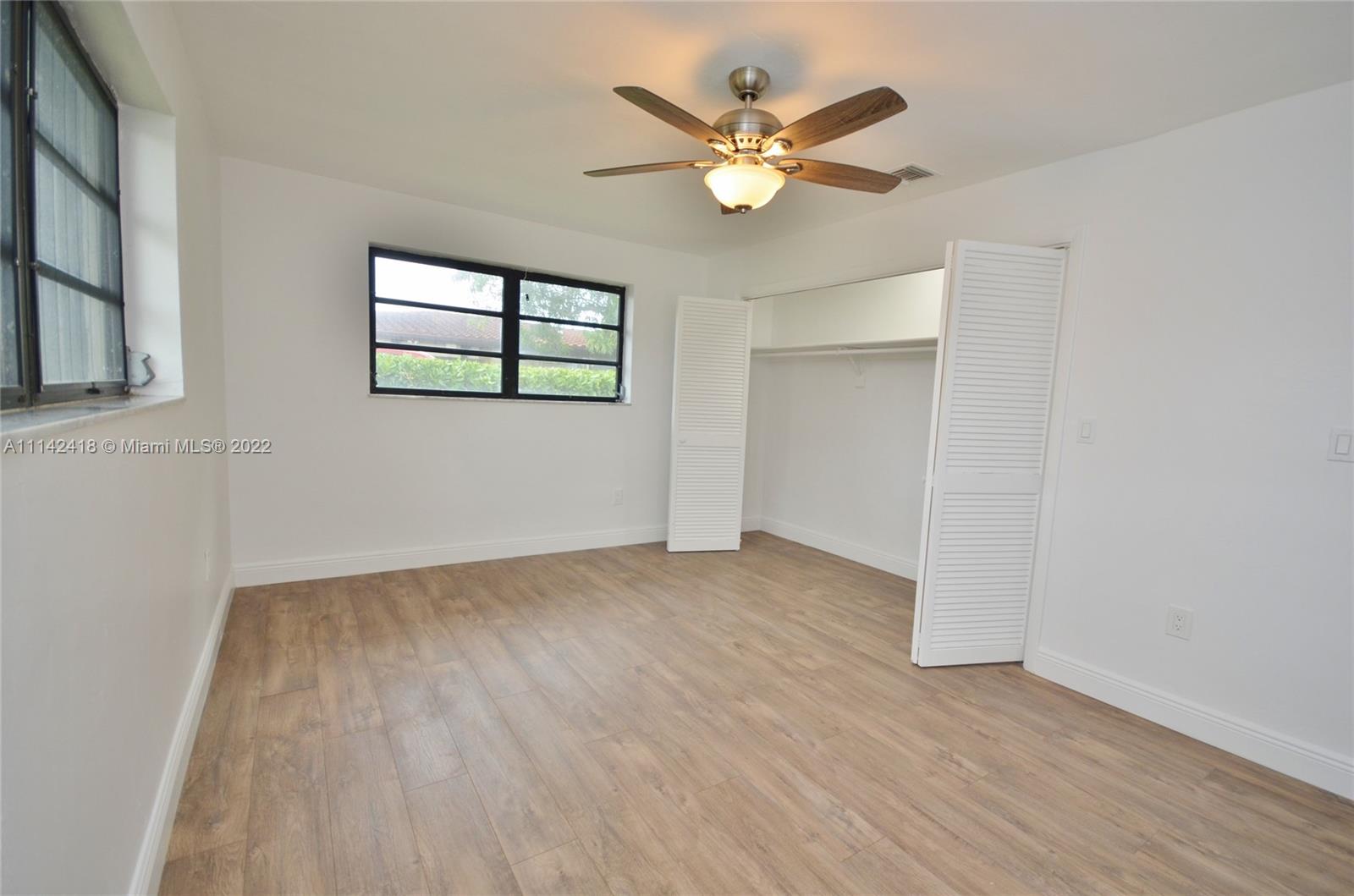 6760 Royal Melbourne Drive Hialeah, FL 33015 - Photo 30 of 36 an empty room with wooden floor and windows