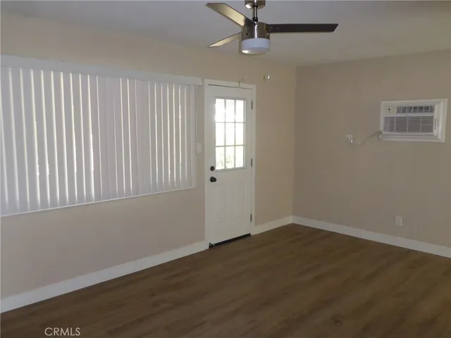 an empty room with wooden floor fan and windows