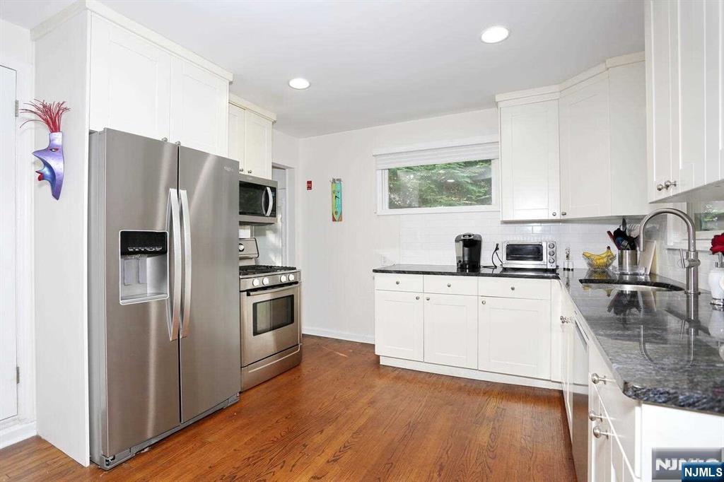 11 Evans Road Cresskill, NJ 07626 - Photo 9 of 31 a kitchen with a refrigerator a stove top oven a sink and dishwasher with wooden floor