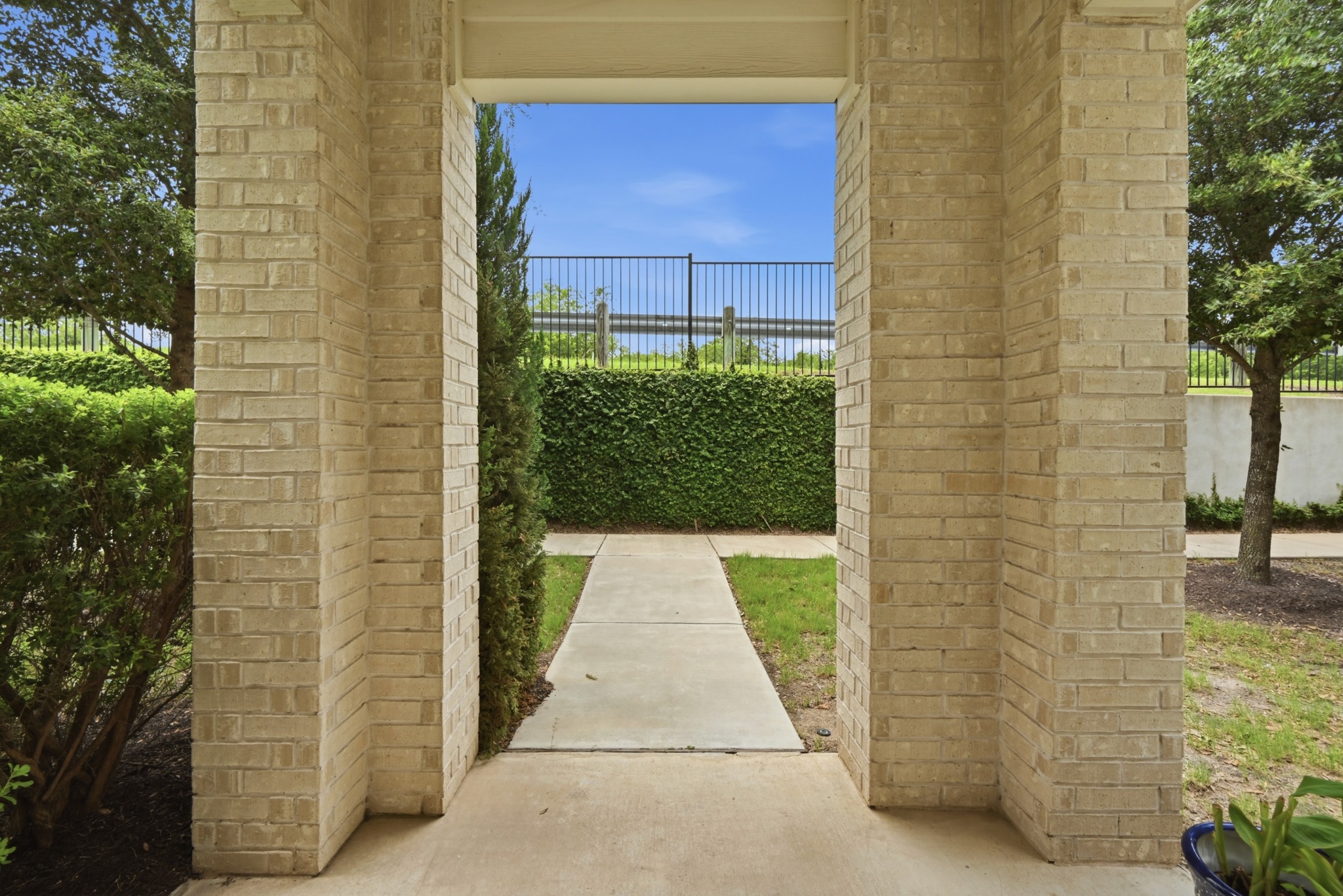 8201 Frida Bend Austin, TX 78744 - Photo 7 of 29 A welcoming entryway framed by robust brick columns, leading to a neatly manicured landscape.