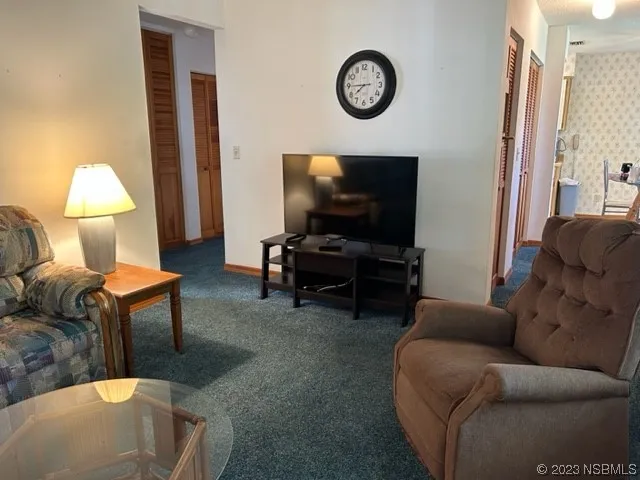 a living room with furniture a flat screen tv and a window