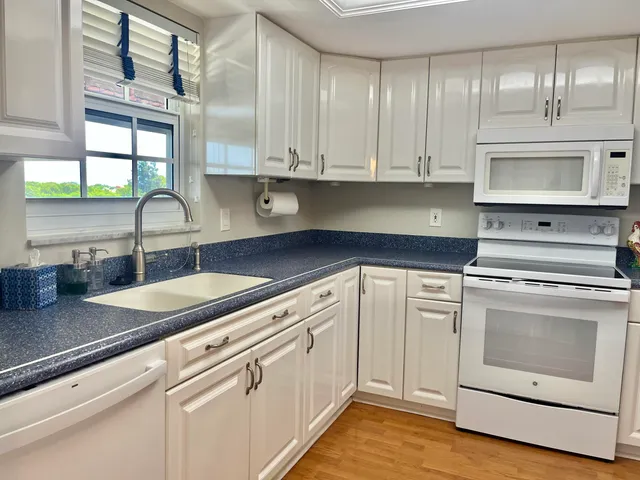 a kitchen with granite countertop white cabinets and white appliances
