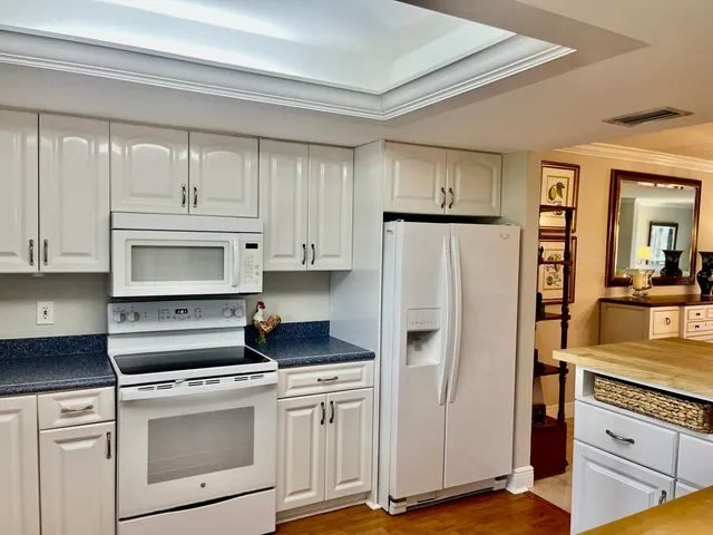 a kitchen with granite countertop white cabinets and refrigerator